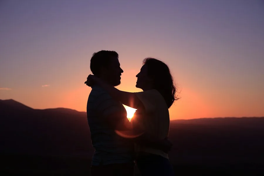 Couple embracing in silhouette at sunset (illustrative stock photo)