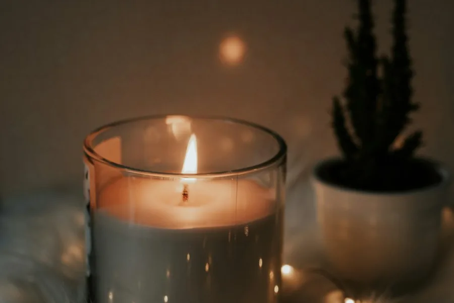 Lit candle glowing on a cosy table (illustrative stock photo)