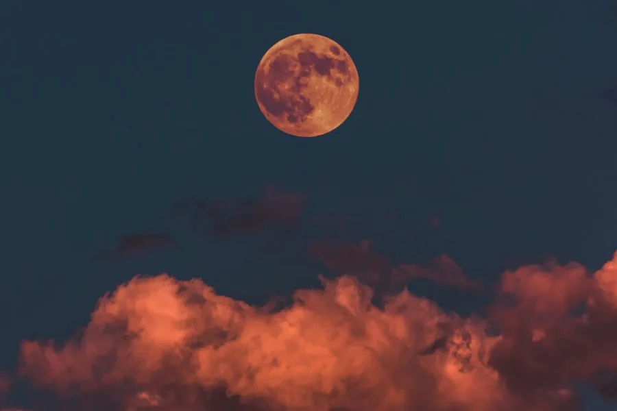 Full moon rising above glowing clouds (illustrative stock photo)