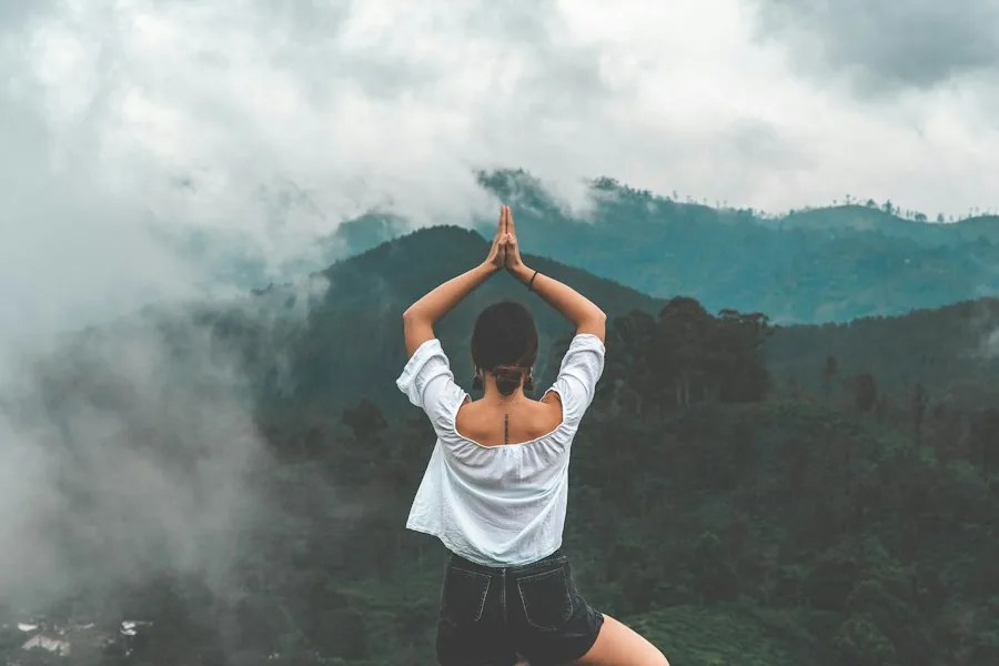 Woman in a yoga pose on a misty mountain top (illustrative stock photo)