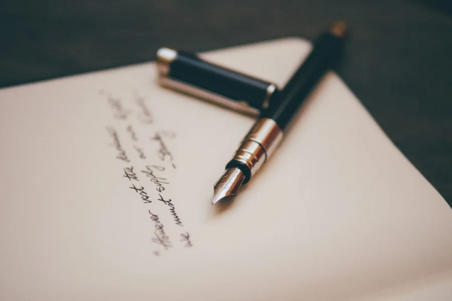 Fountain pen resting on a handwritten page (illustrative stock photo)