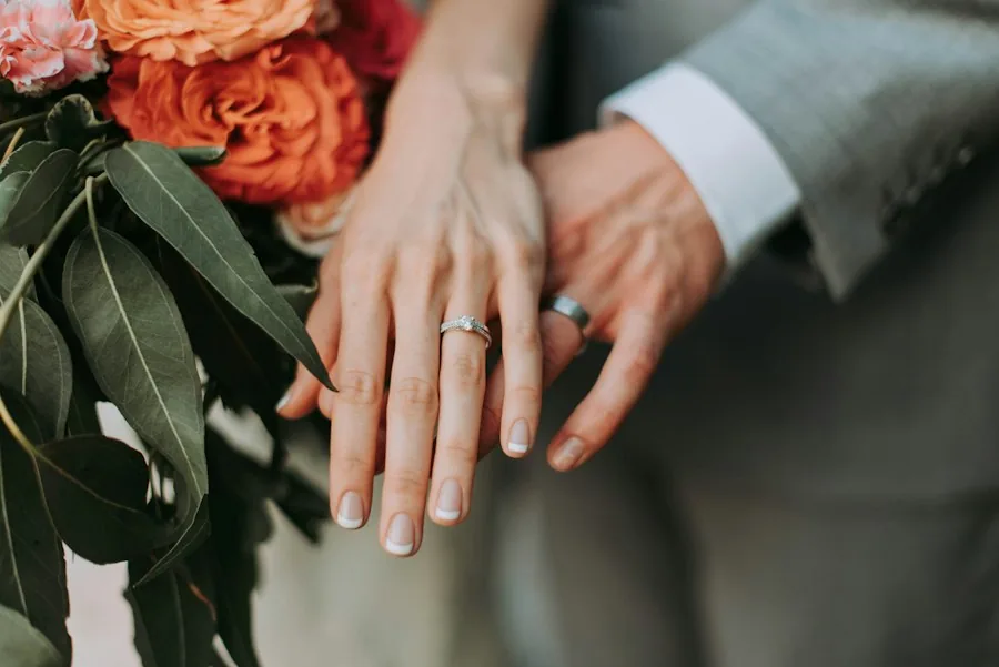 Couple holding hands, showing their wedding rings (illustrative stock photo)