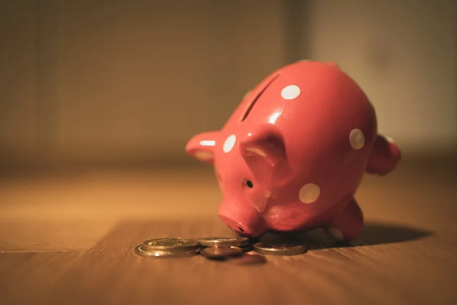 Red piggy bank on a wooden table (illustrative stock photo)